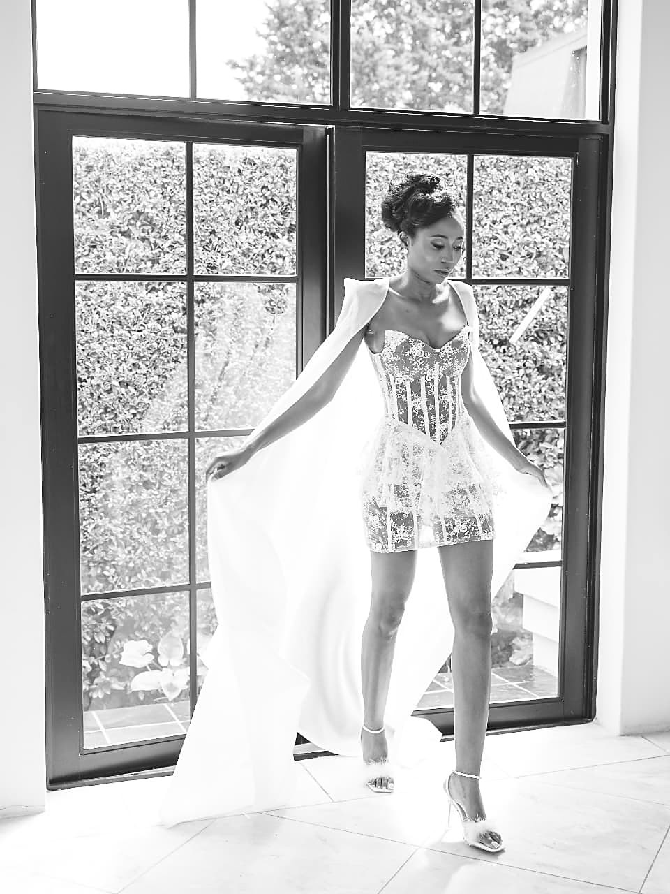 Lace corset mini worn with a detachable satin shoulder cape falling into a full train