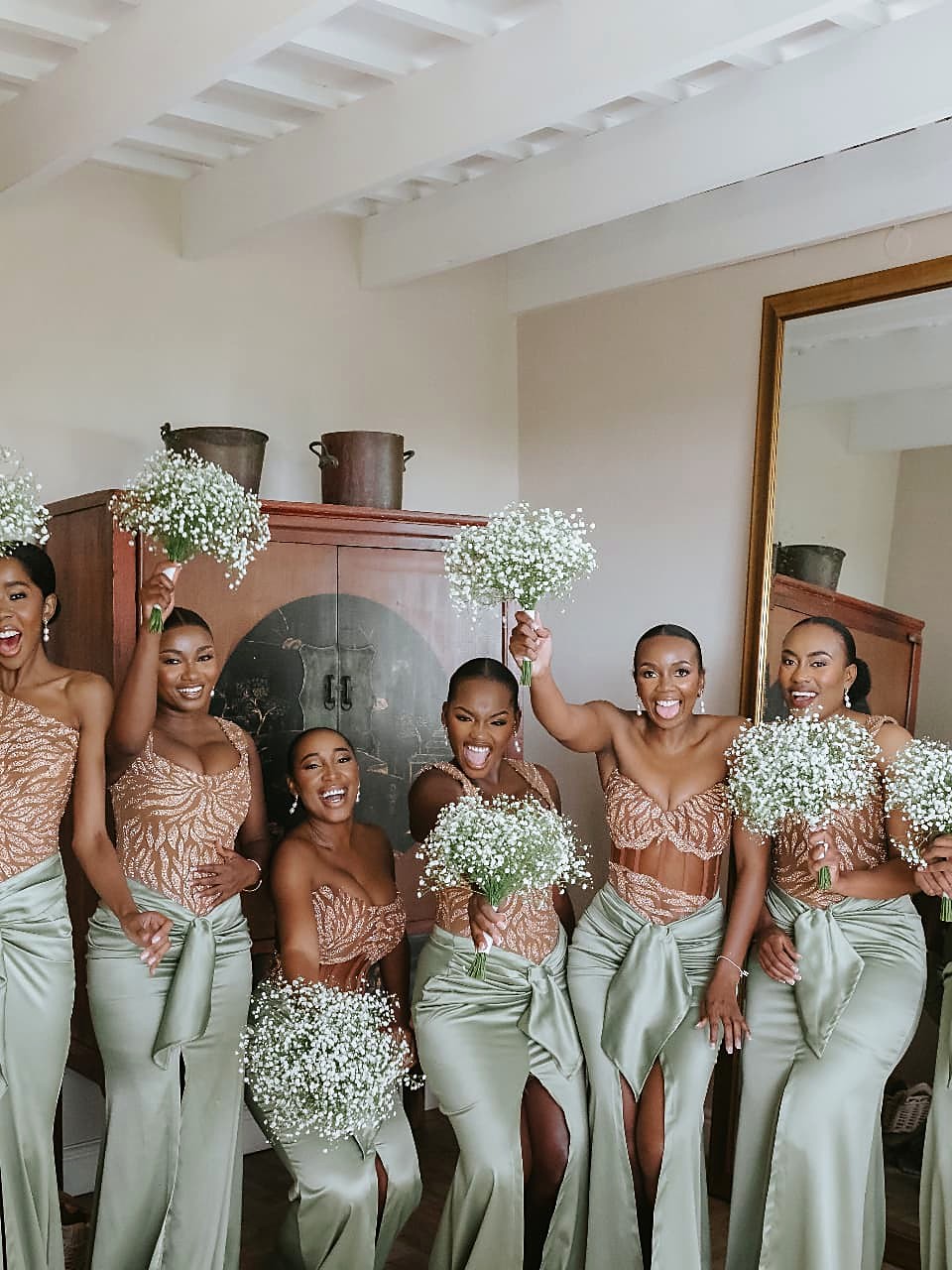 The same bridal party celebrating, showing the bow drapes and high slits of the sage satin skirts