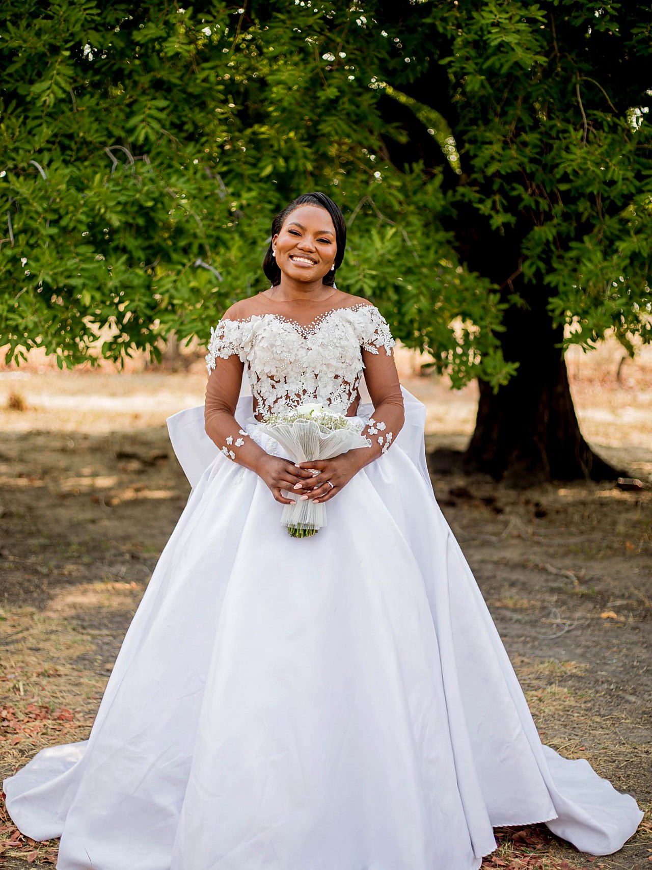 Bride in an ivory silk mikado ball gown with a 3D floral lace illusion bodice and long sheer sleeves