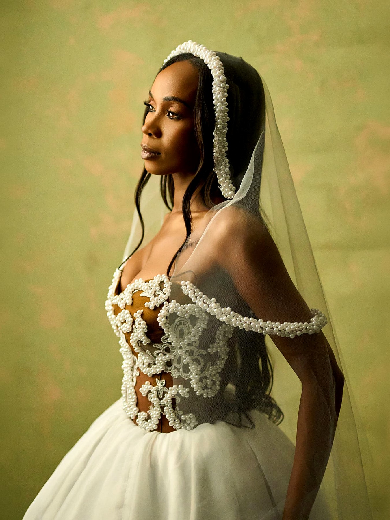 Side view of the pearl illusion corset gown with the veil falling over the shoulder
