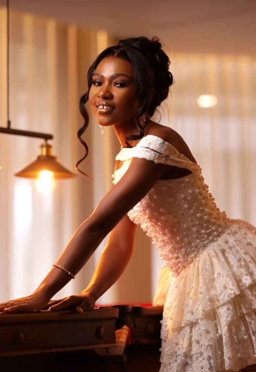 Bride in pearl-encrusted short gown leaning over a wooden table in warm lamplight