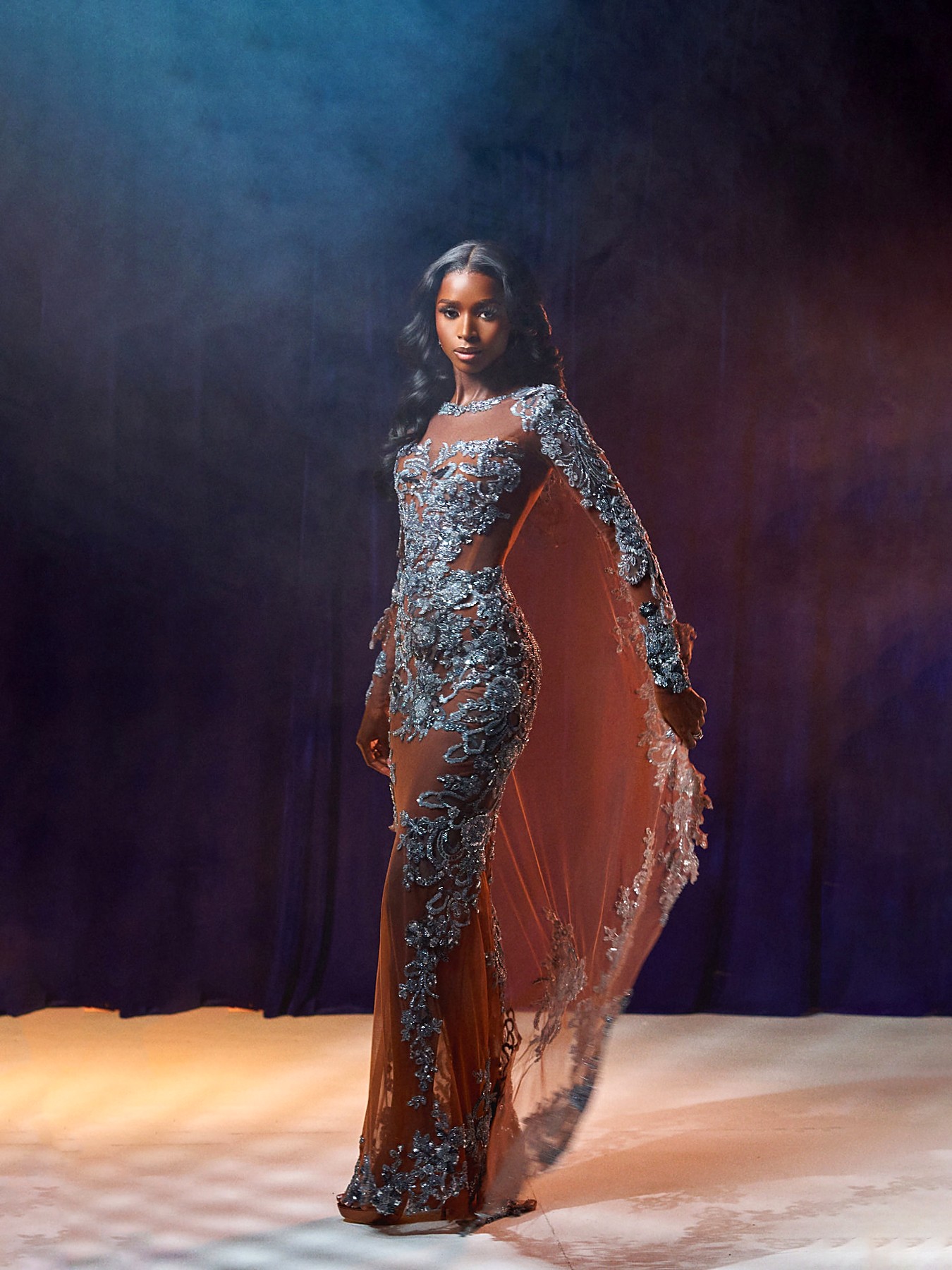 Side view of the silver beaded illusion gown with the cape held open
