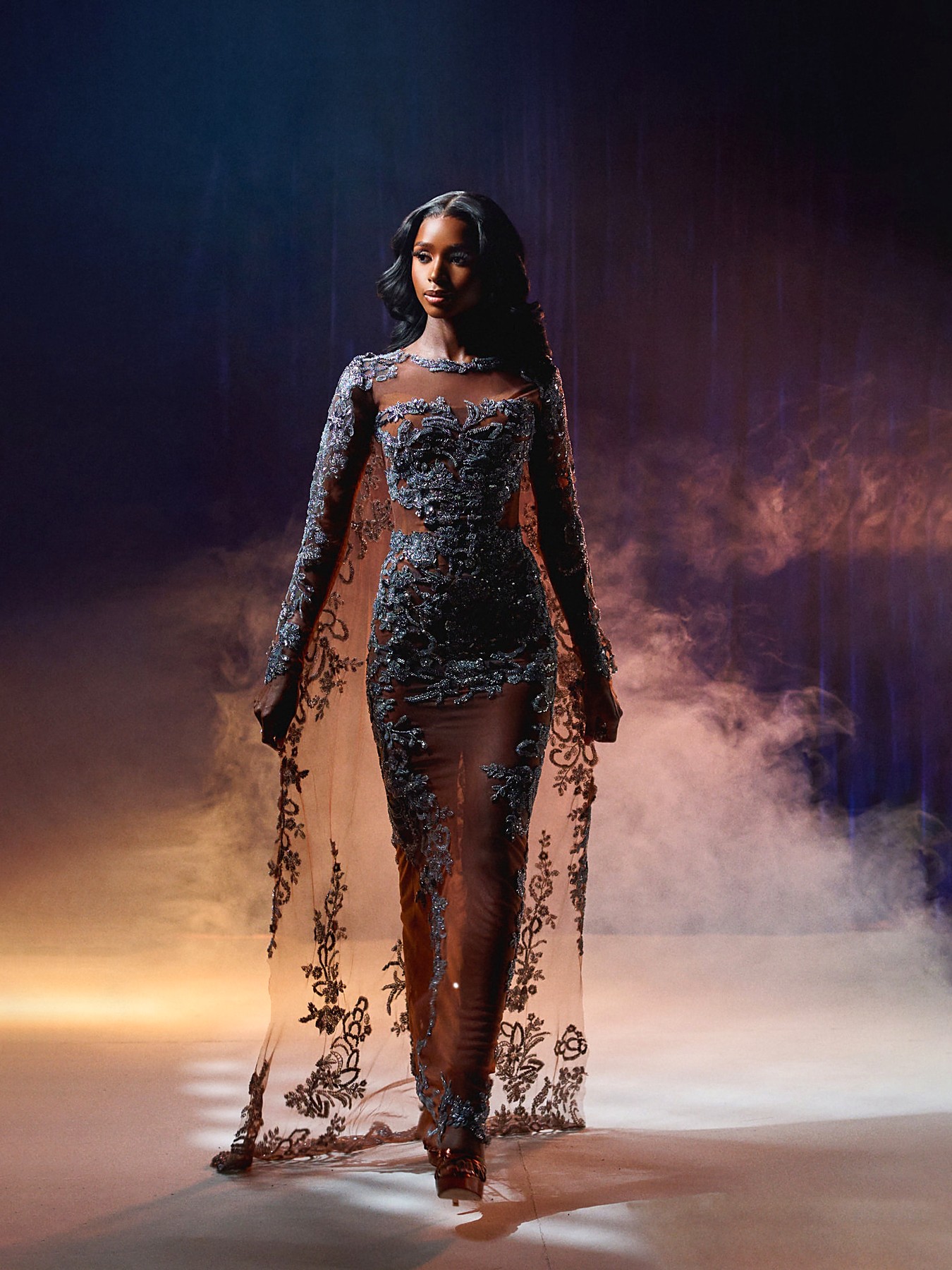 Silver hand-beaded illusion gown with a full floor-length embroidered cape on the runway